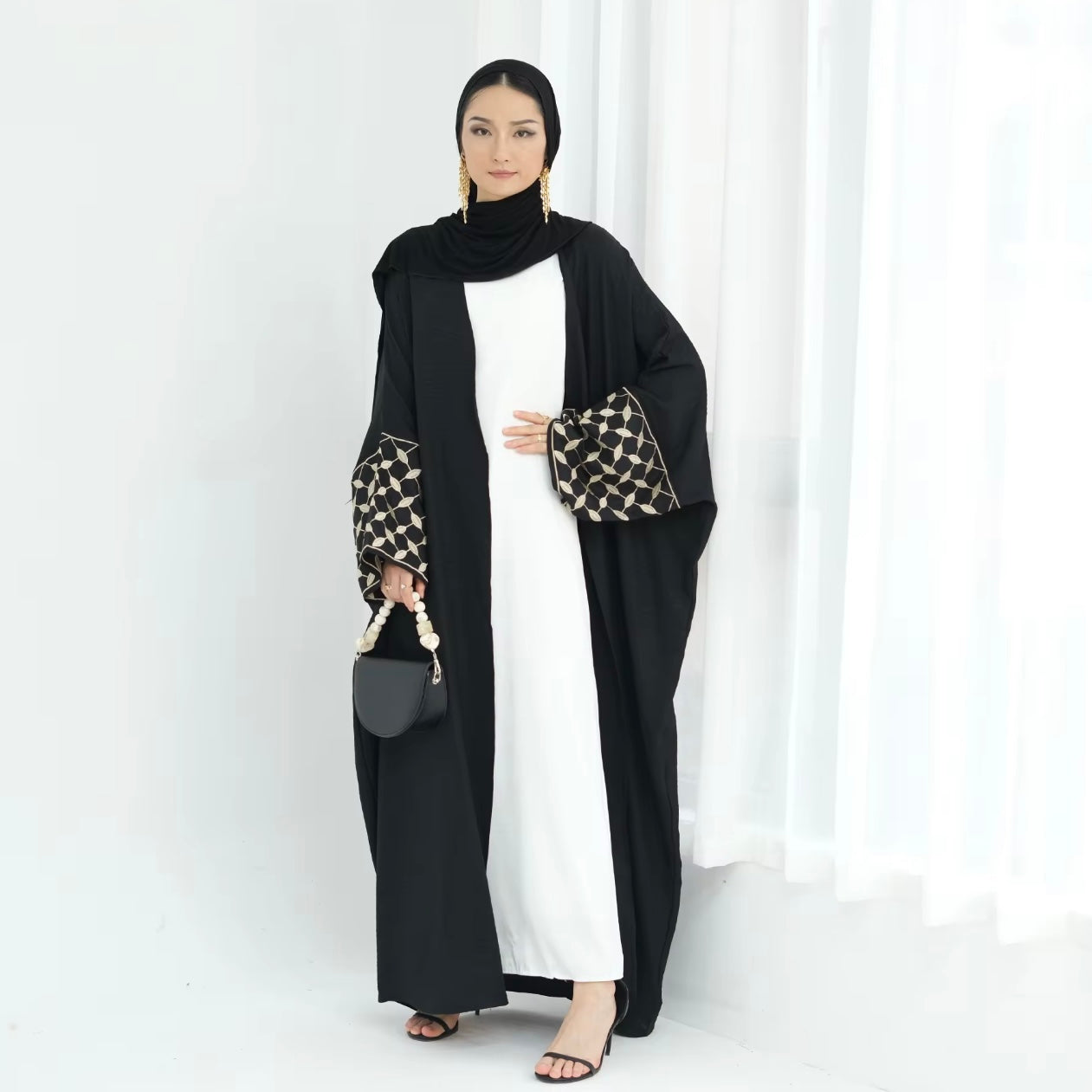 Woman wearing a black and white outfit with a patterned sleeve on a white background
