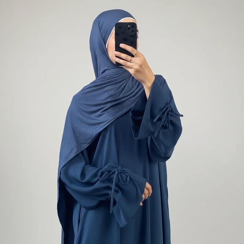 Person wearing a blue abaya taking a mirror selfie.