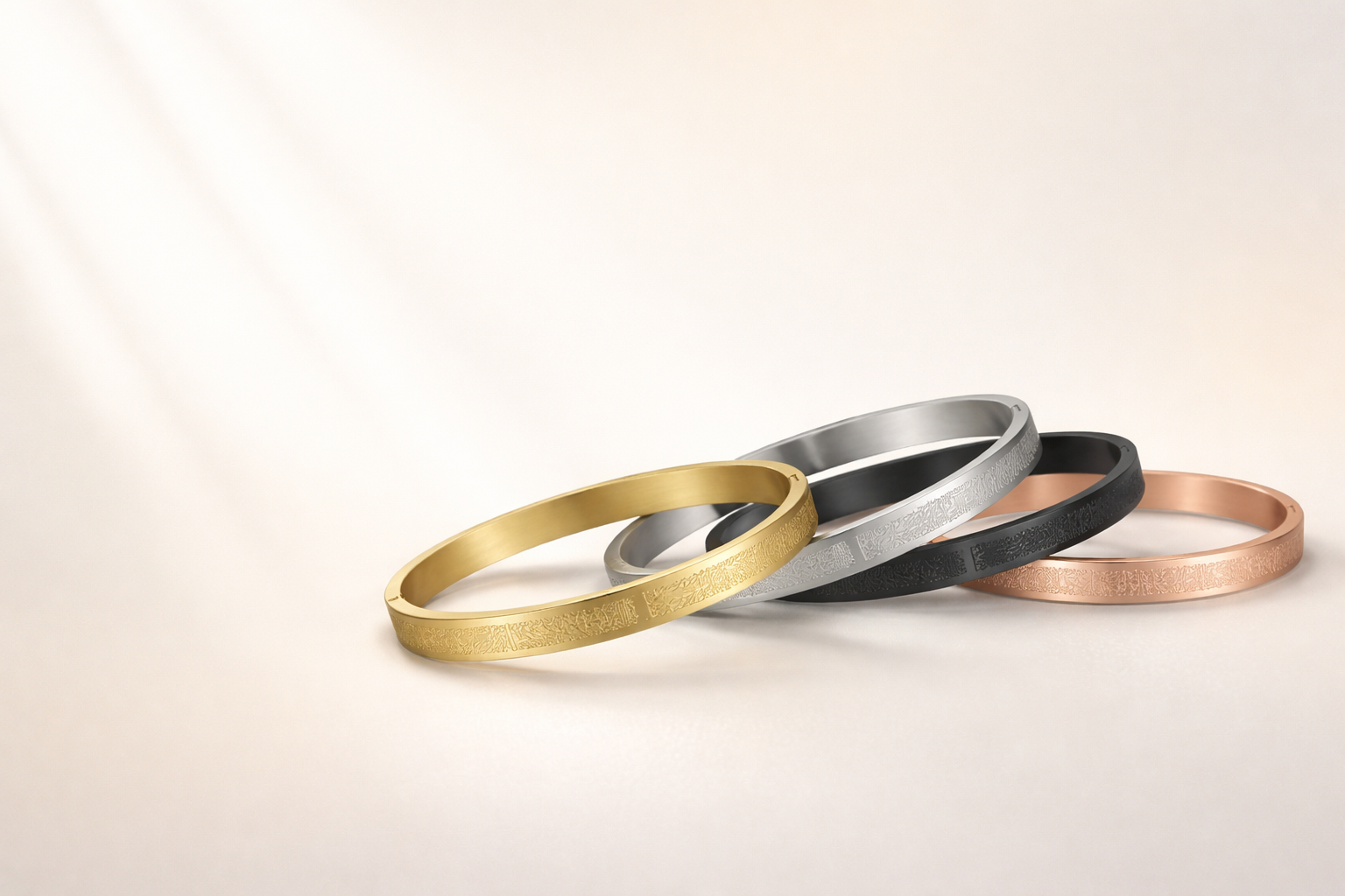 Luxury Ayatul Kursi bracelets in gold, silver, black, and rose gold, arranged on an ivory background