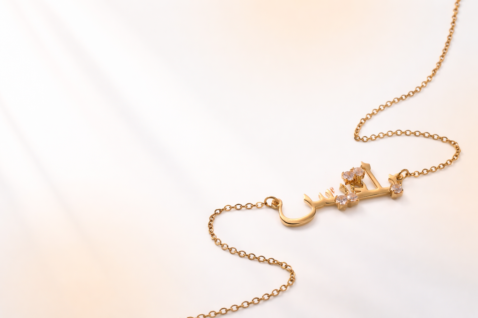 Luxury gold Arabic name necklace with diamond accents, shown on an ivory background for a jewelry website banner
